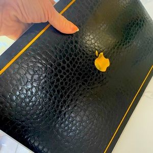 MacBook Pro black leather hard case cover with gold detail.